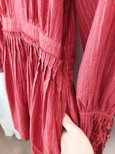 Close-up of a red pleated garment with a blurred background